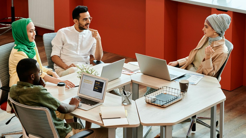 Colleagues collaborating around a meeting table with laptops in a modern office.